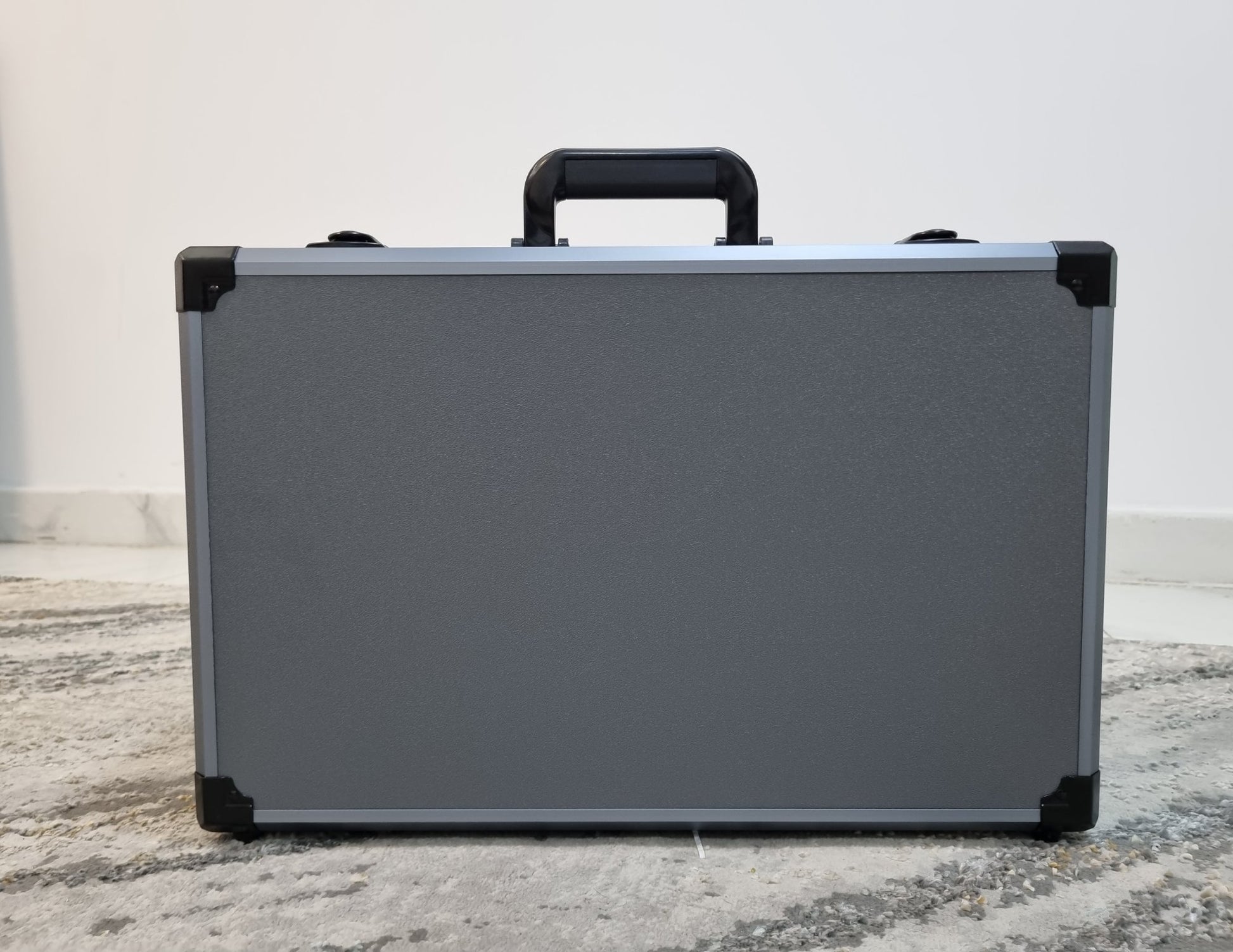 Silver briefcase with black handles and corners on a marble surface