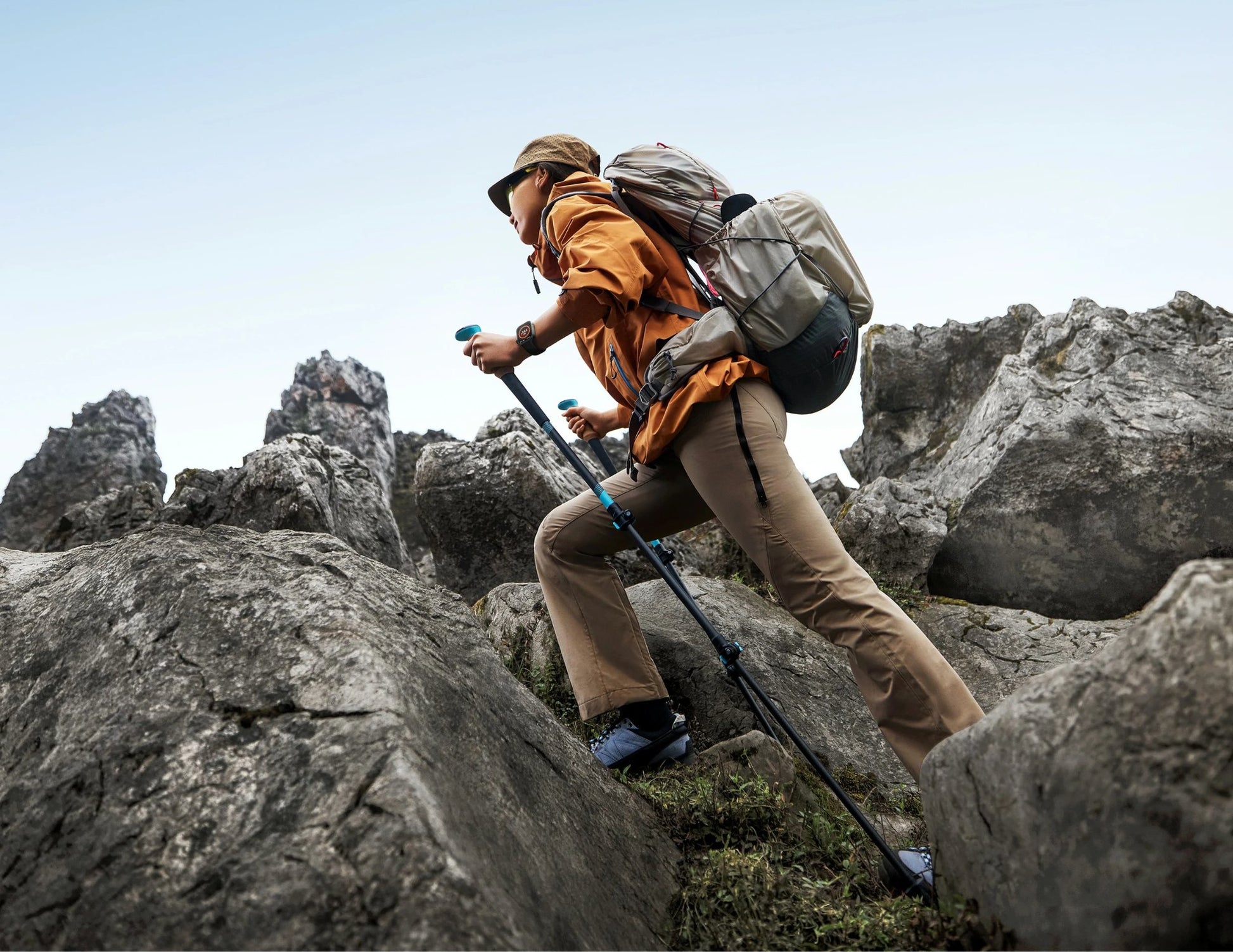 Person hiking on rocky terrain with backpack and walking sticks