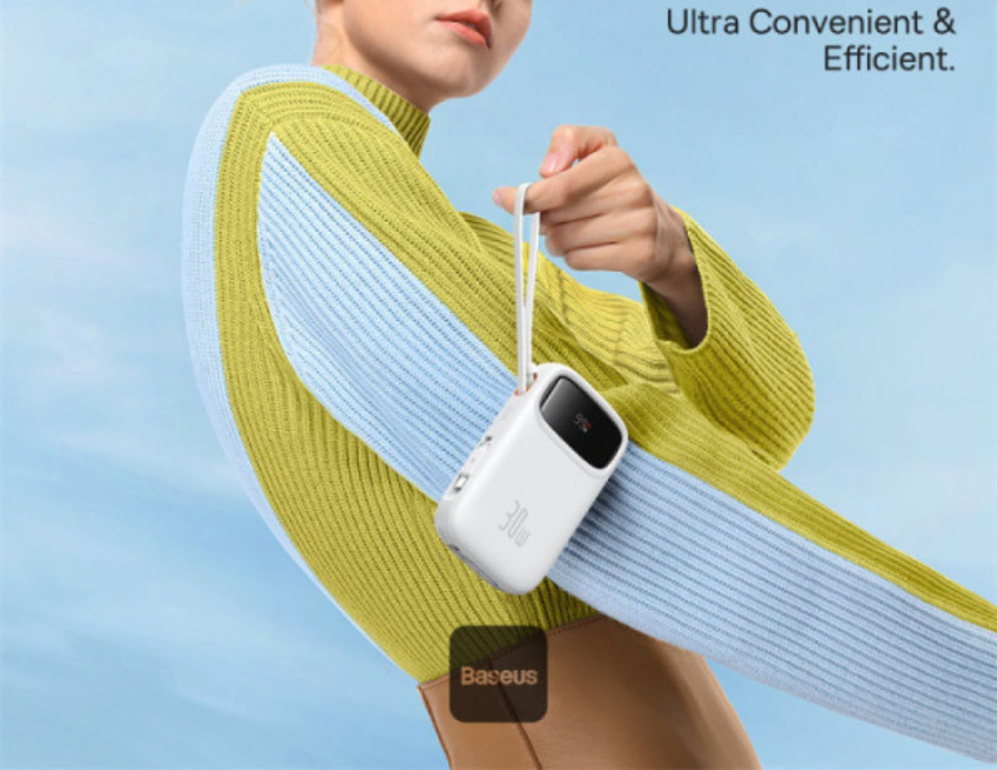 Person wearing a yellow sweater holding a white device with 'Baseus' branding against a blue sky.