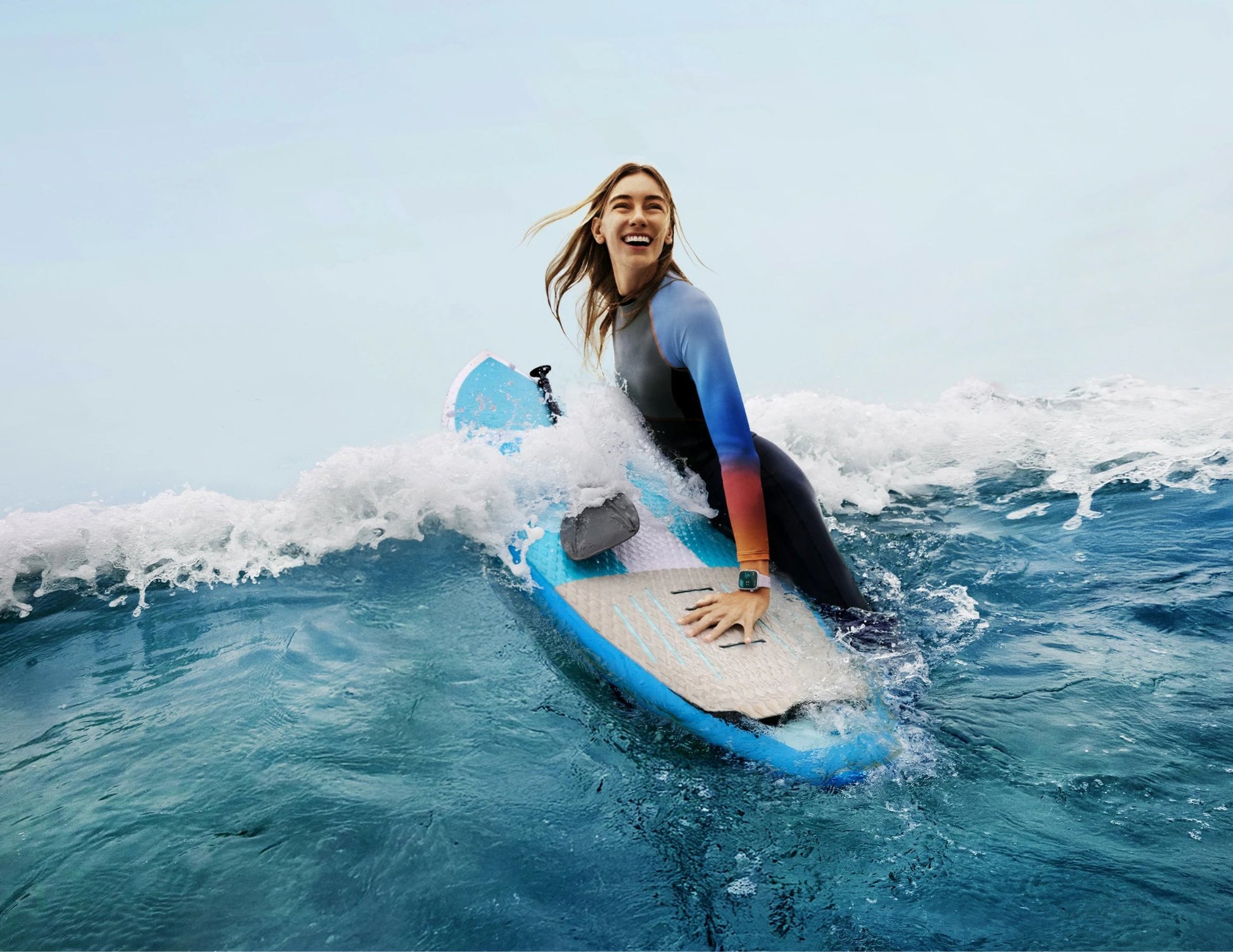 Person surfing on a blue wave with a clear sky