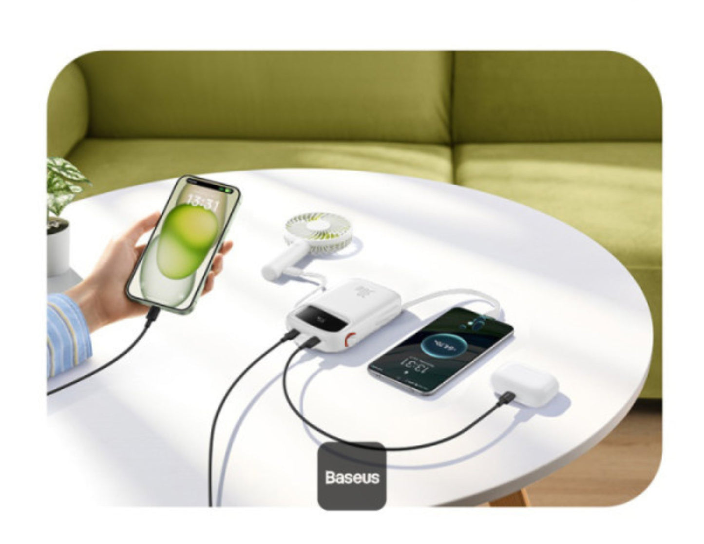 Multiple electronic devices being charged by a Baseus power bank on a table with a green sofa in the background.
