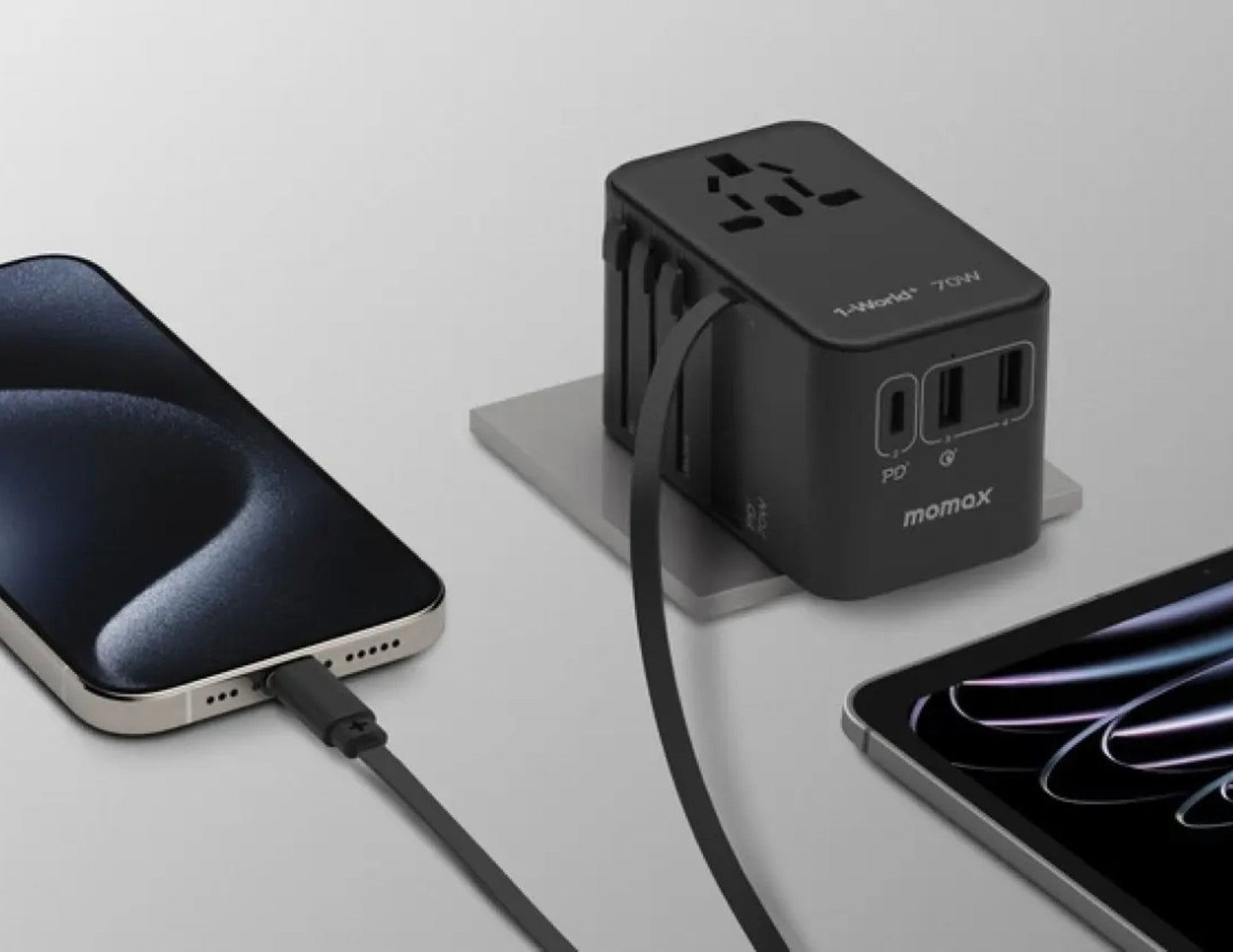 Black Momax 1‑World+ 70W GaN 3‑Port Travel Adapter with Retractable USB‑C Cable – UA18 connected to a smartphone and tablet on a light gray background.