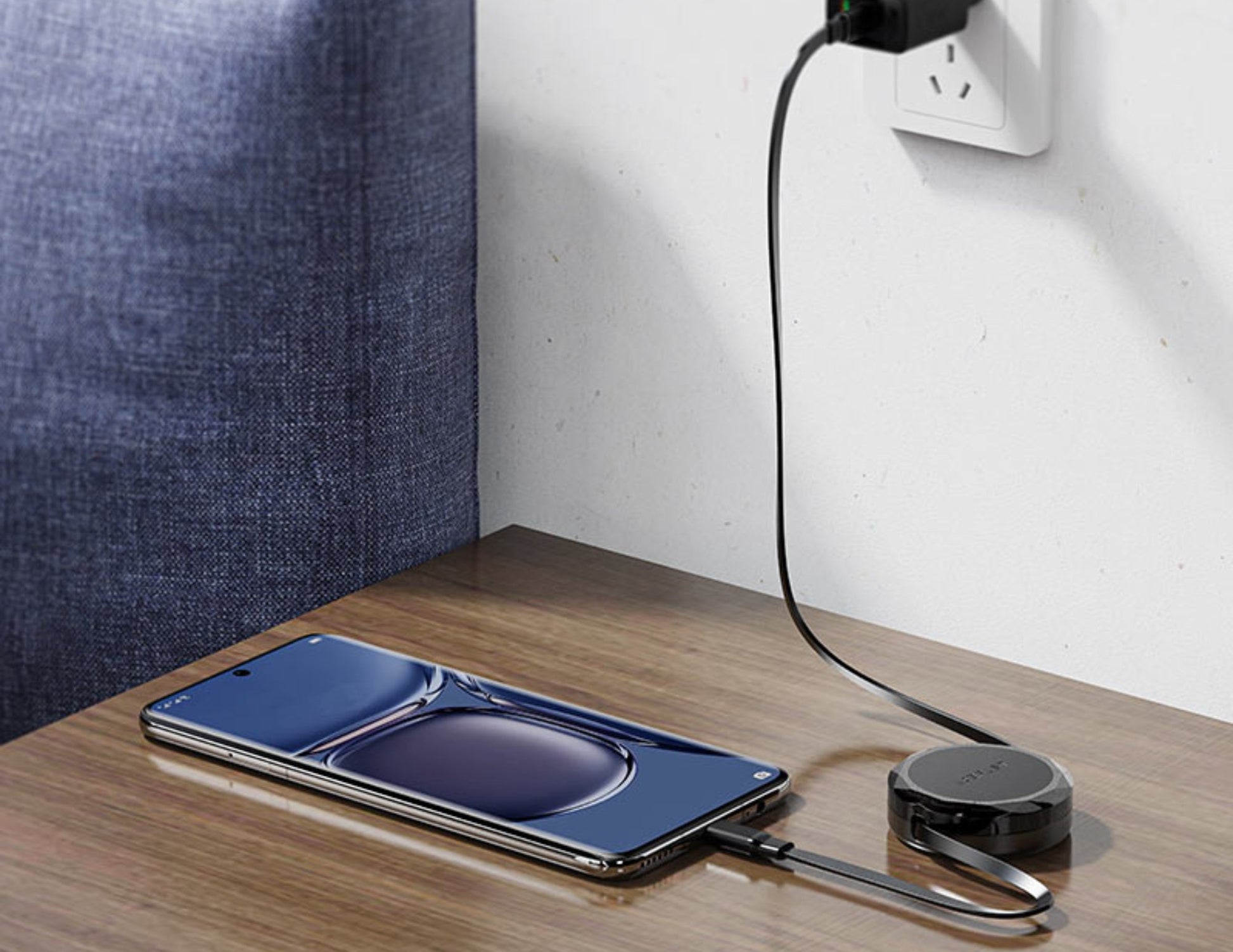 Smartphone with wireless charging pad on a wooden surface, plugged into an outlet.