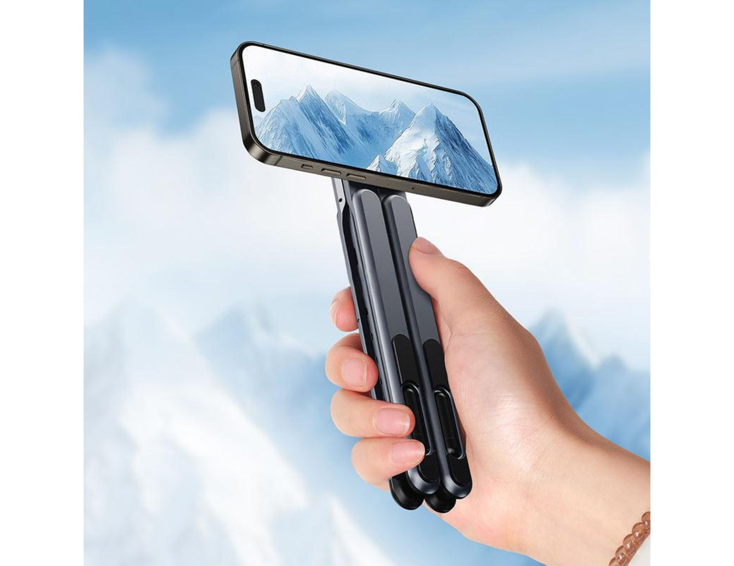 Hand holding a smartphone with a E05 Multi-purpose Travel Portable Stand (5-in-1, Magnetic, Waterproof) on the screen against a blue sky.