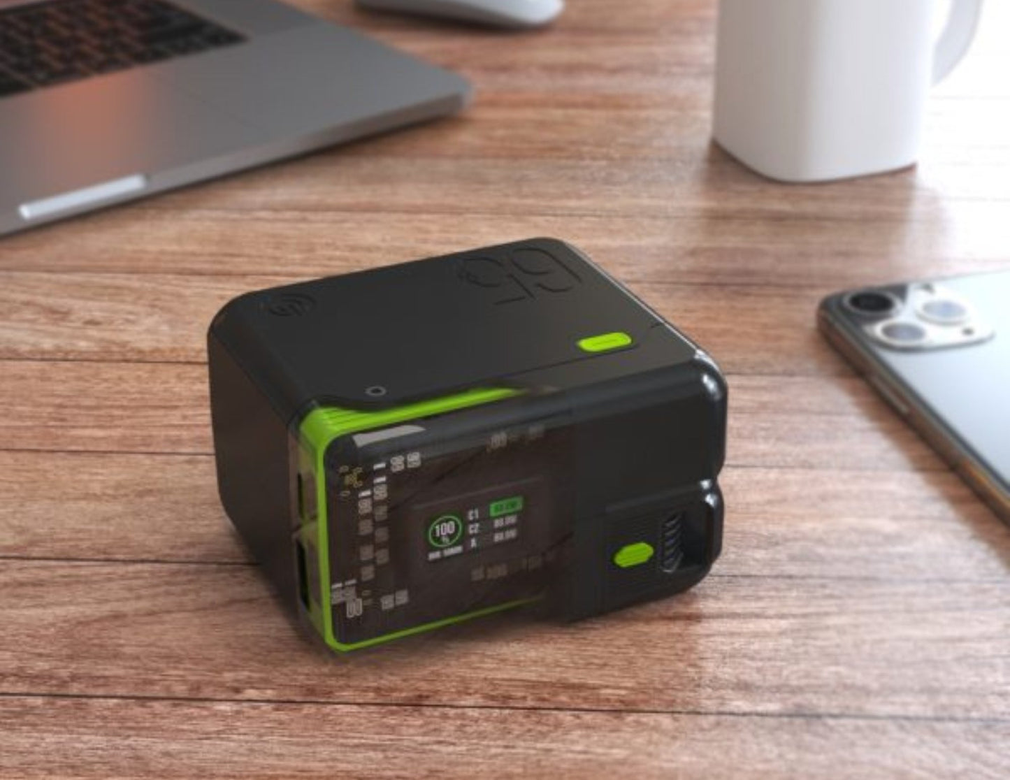 Black and green electronic device on a wooden desk with a laptop and phone in the background.