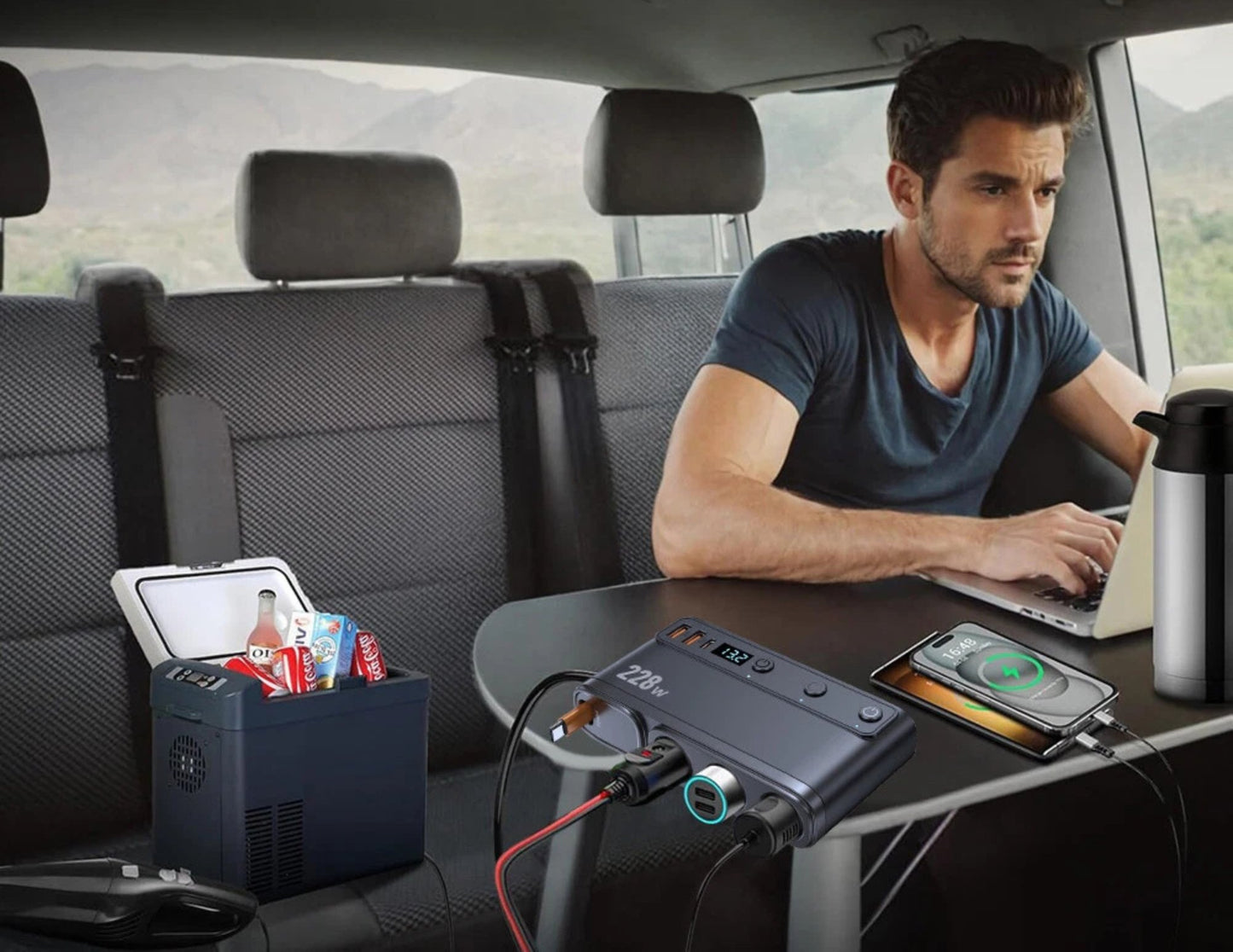Man using a portable power station in the back of a car with various devices plugged in.
