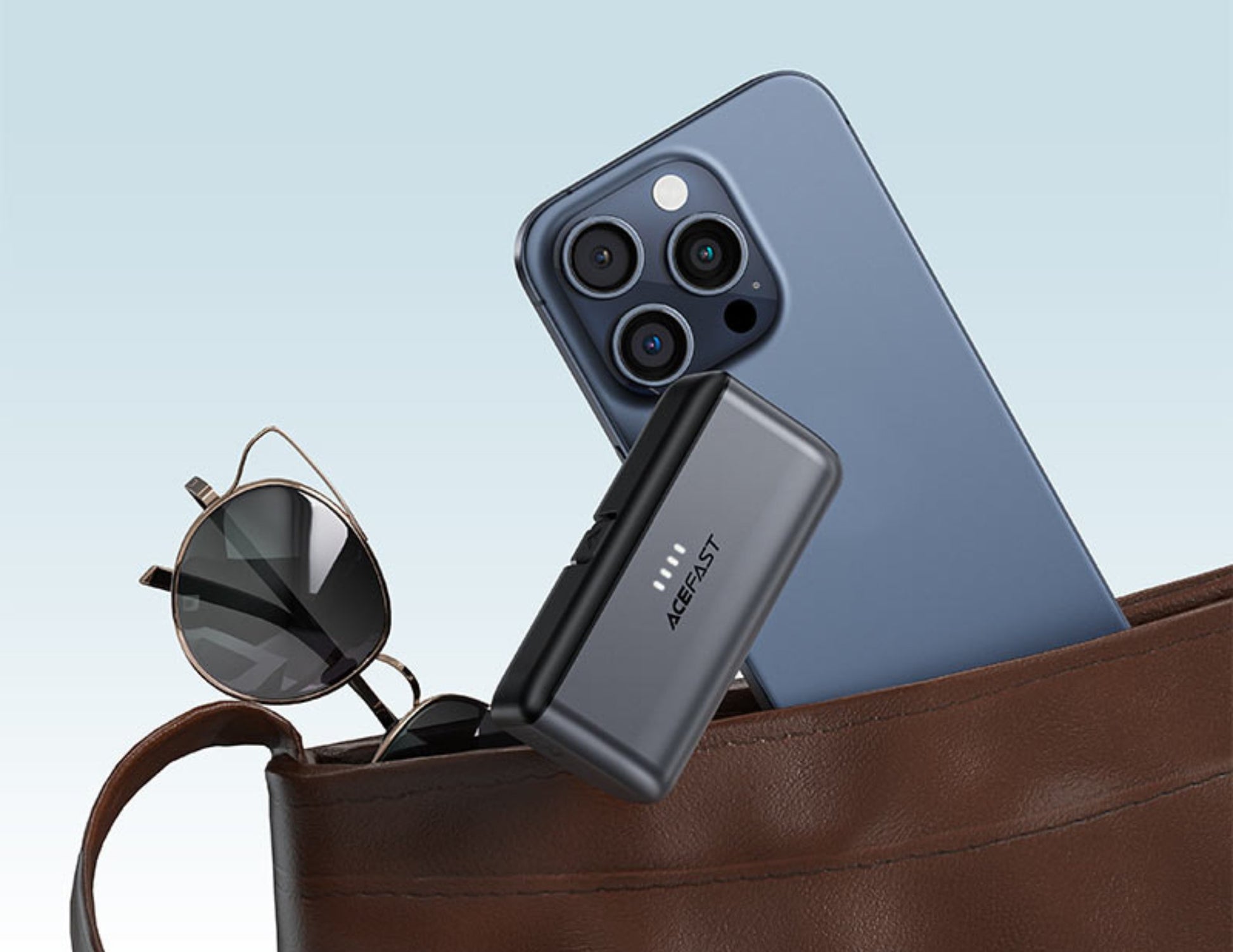 Smartphone, power bank, and sunglasses in a brown leather bag with a light blue background