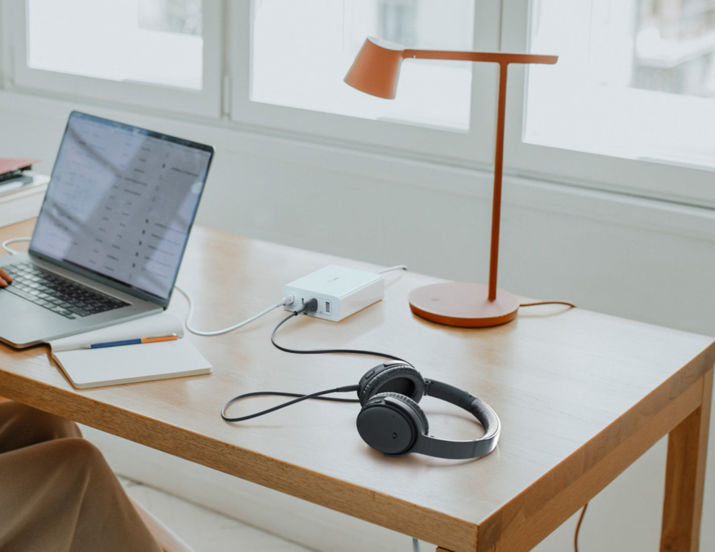 Laptop, headphones, and desk lamp connected to BELKIN BoostCharge Pro 108W 4-Port GaN Charger with 2 USB-C & 2 USB-A Ports – WCH010myWH on a wooden desk with a window in the background
