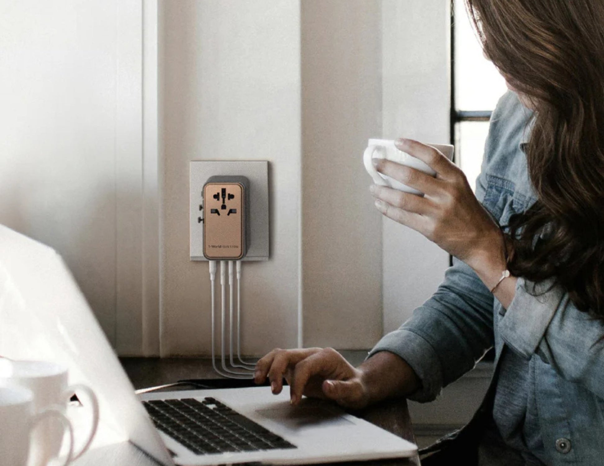 Person using a laptop with a power adapter on a wall socket in the background