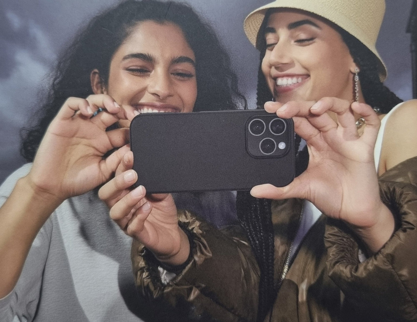 Two women holding a smartphone together, smiling.