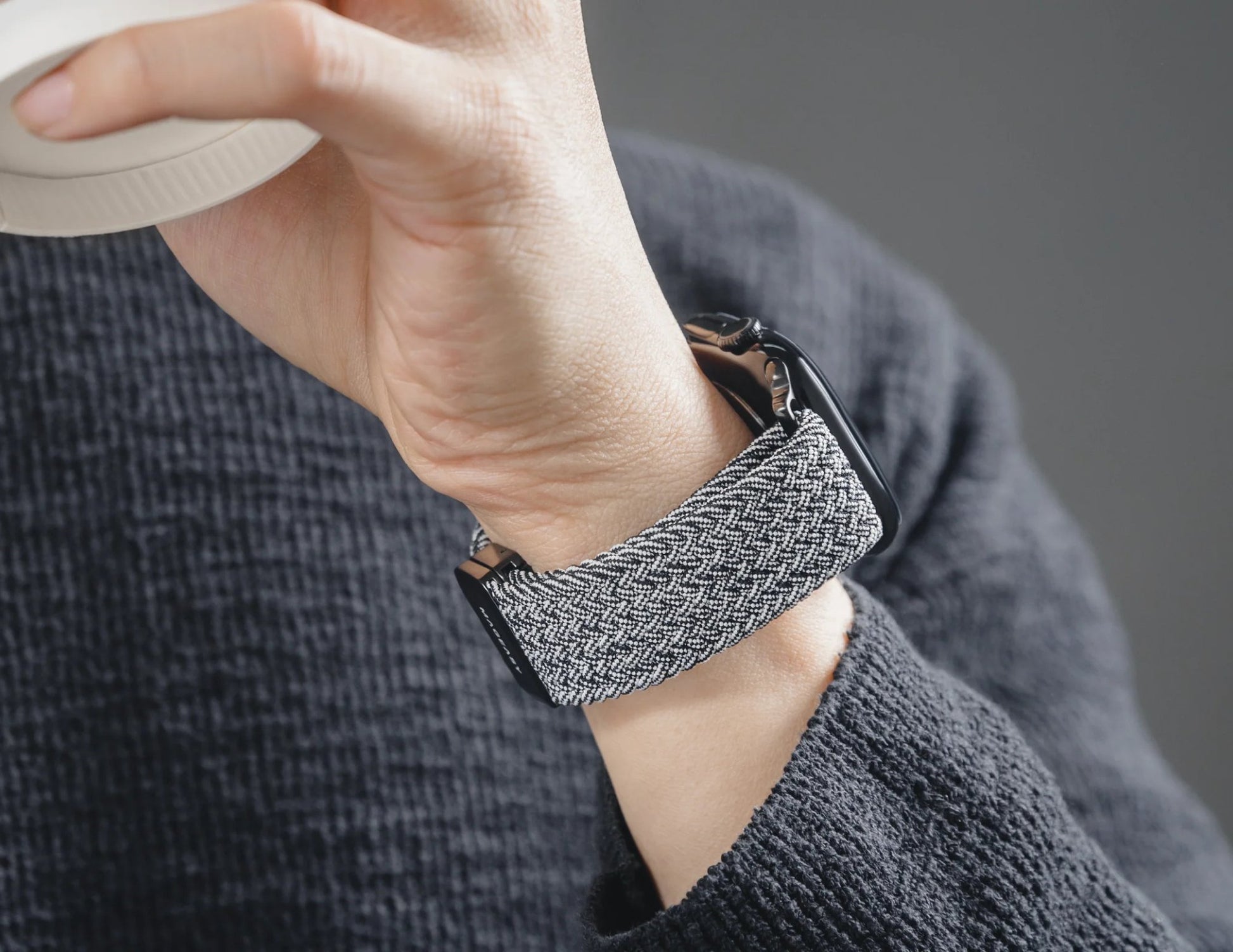 Person wearing a textured gray smartwatch on their wrist.