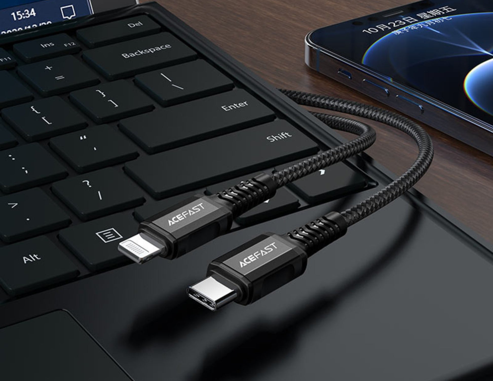 A black APELFast cable on a laptop keyboard with a smartphone in the background.