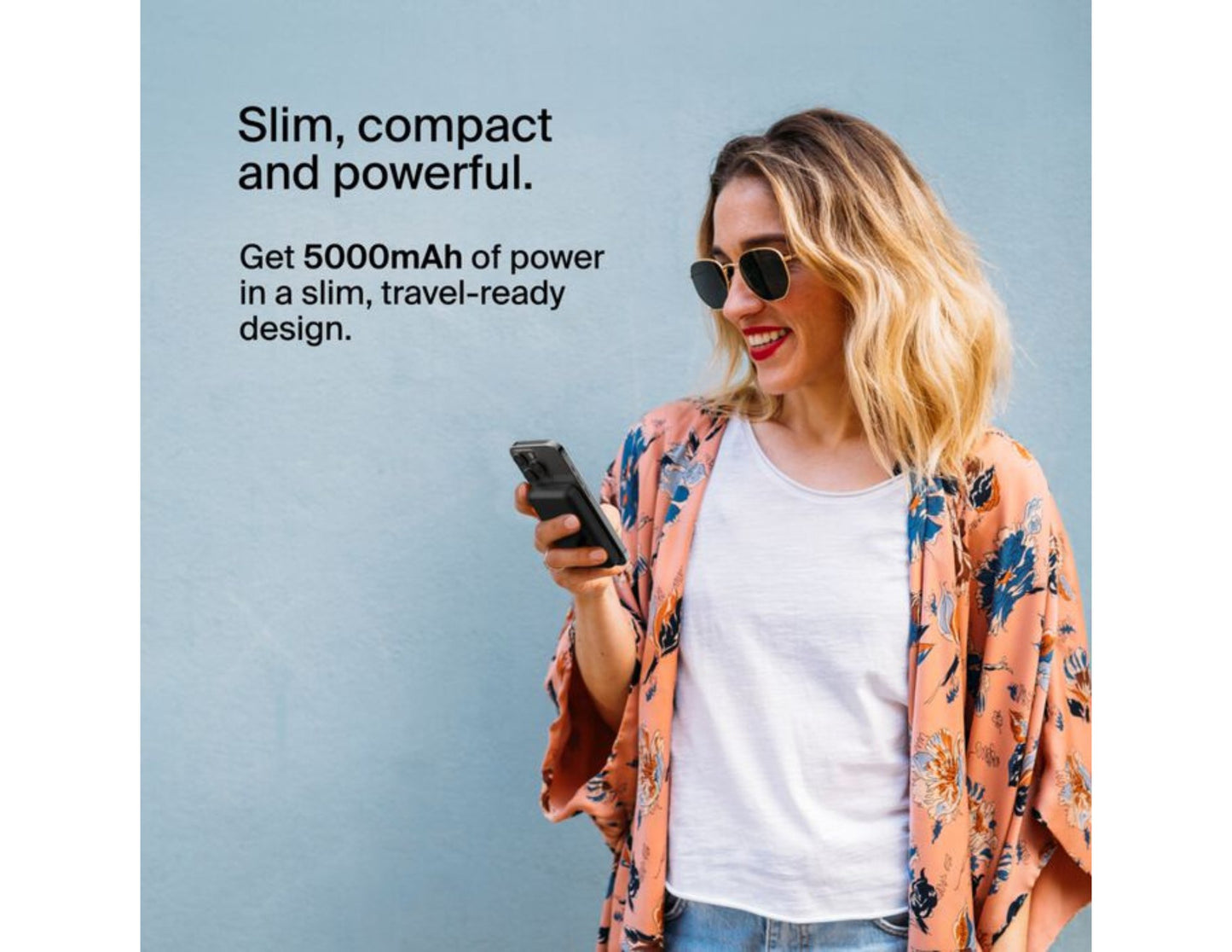 Woman holding a phone with Belkin BoostCharge Magnetic Wireless Power Bank 5000mAh with Fold-out Stand – BPD004btBK – Black and promotional text about power and design on a light blue background