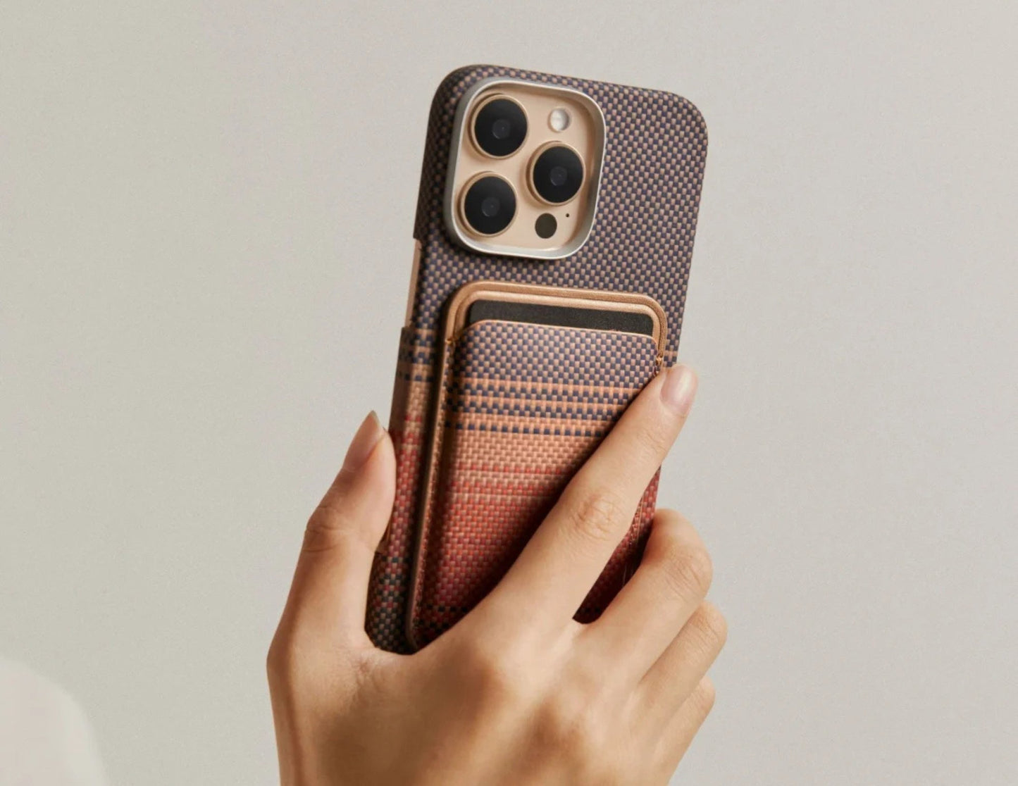 Hand holding a phone with a Pitaka MagSafe Woven Wallet – Magsafe Compatible MWW240 against a neutral background