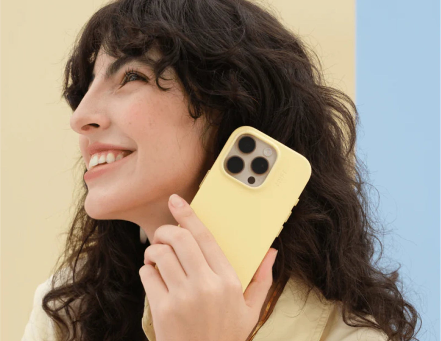 Woman holding a yellow phone case against a beige and blue background