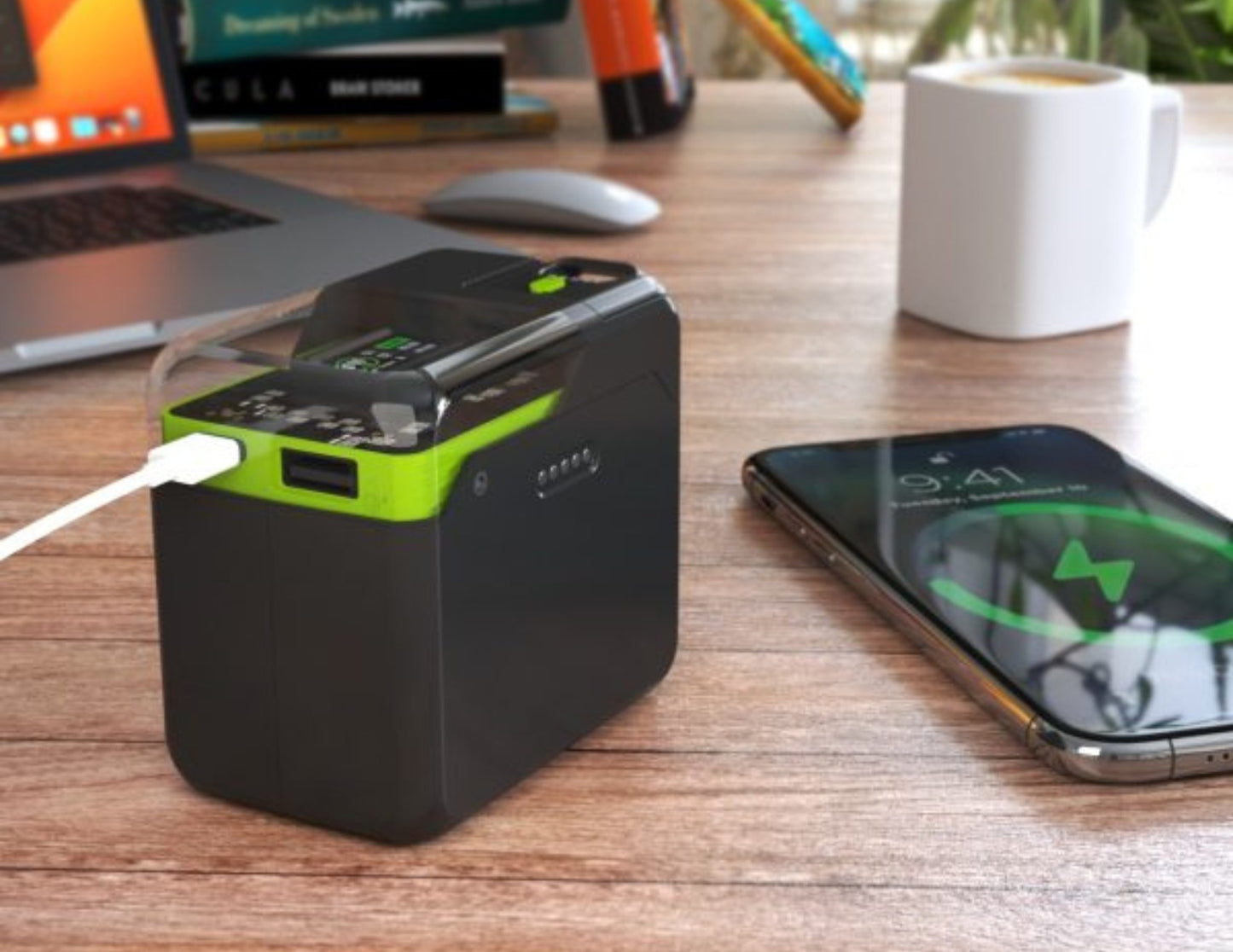 Black power bank with green accents charging a smartphone on a desk.