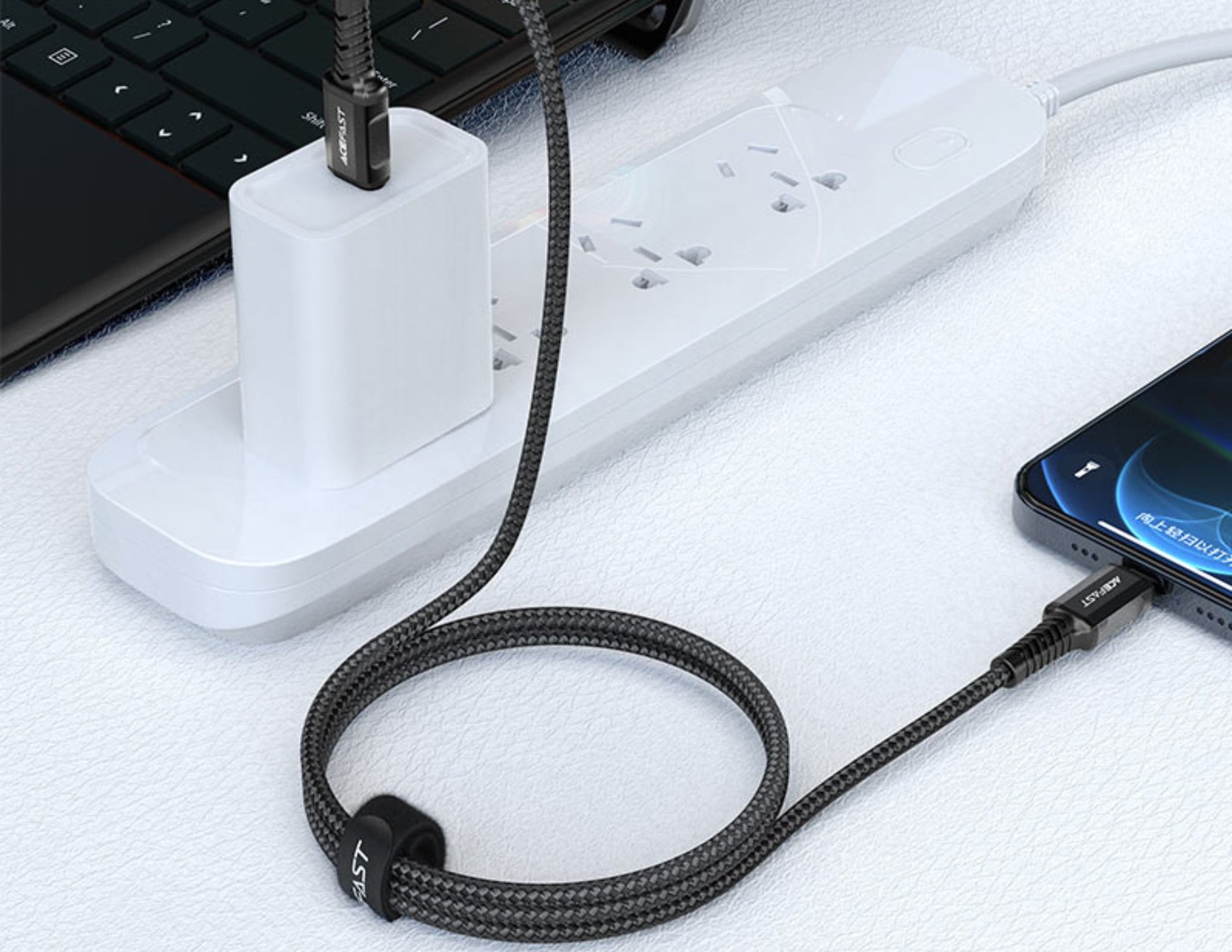 Black braided cable connected to a smartphone and power strip on a white surface