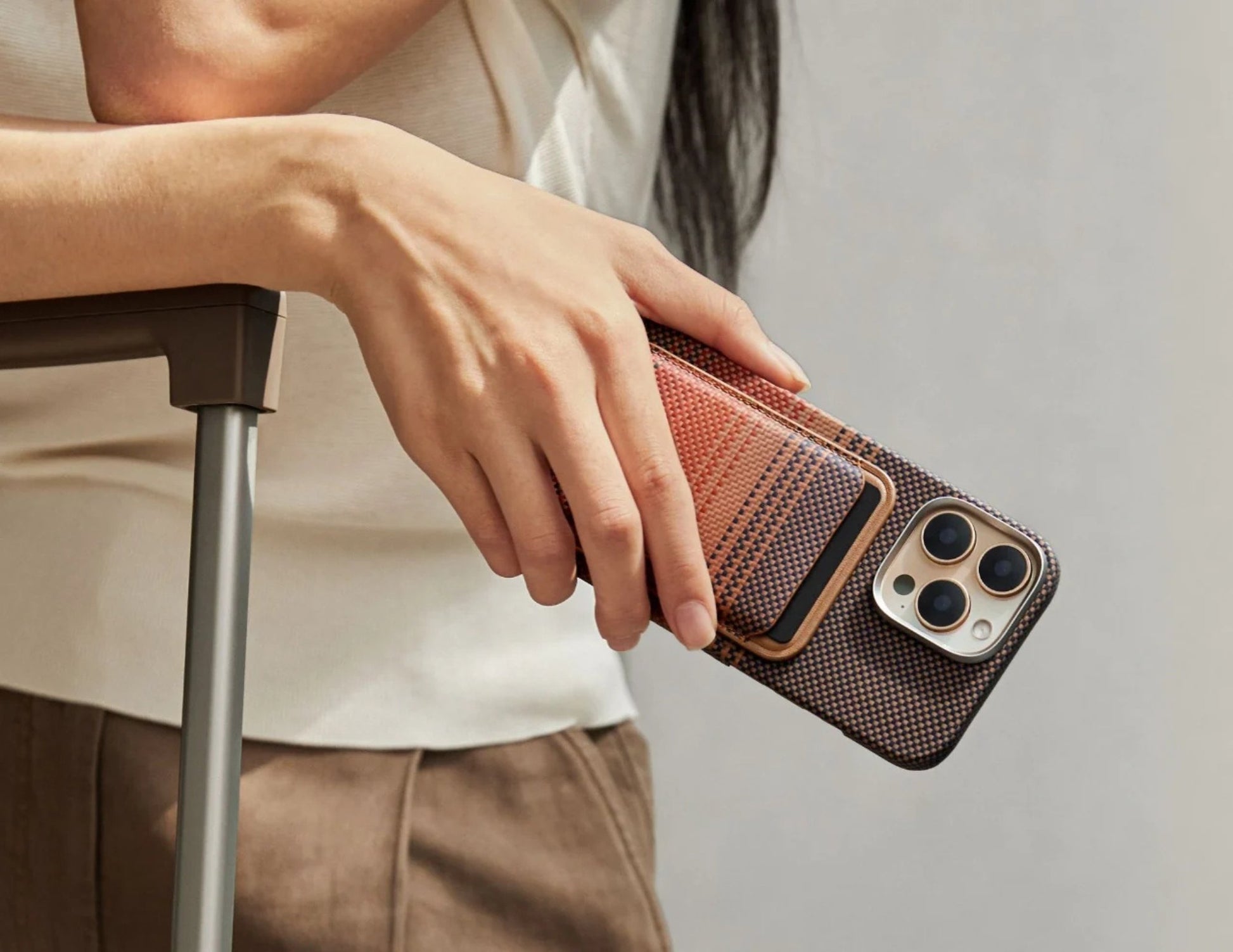 Person holding a phone with a Pitaka MagSafe Woven Wallet – Magsafe Compatible MWW240 against a neutral background