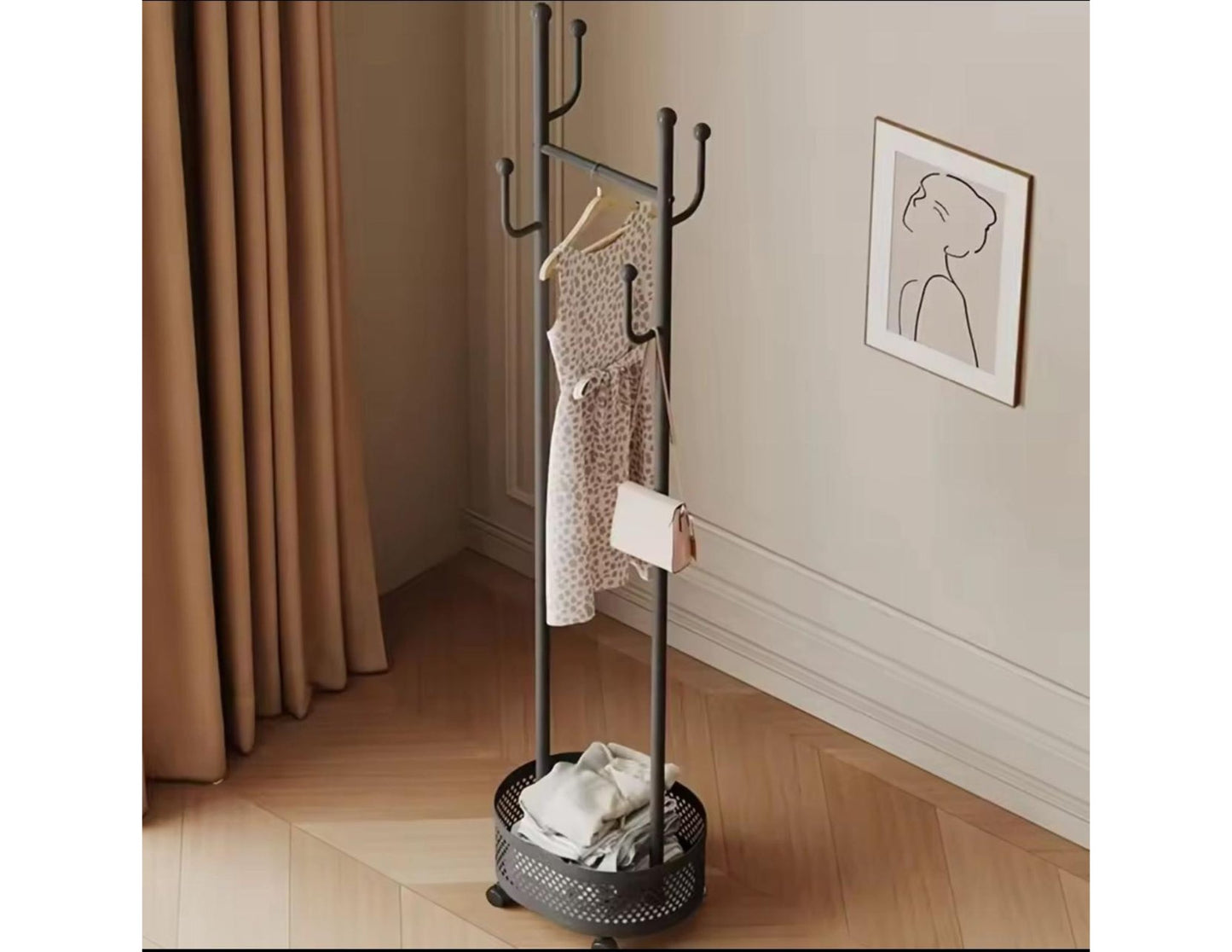 Black metal coat rack with clothes in a room with a curtain and wall art.