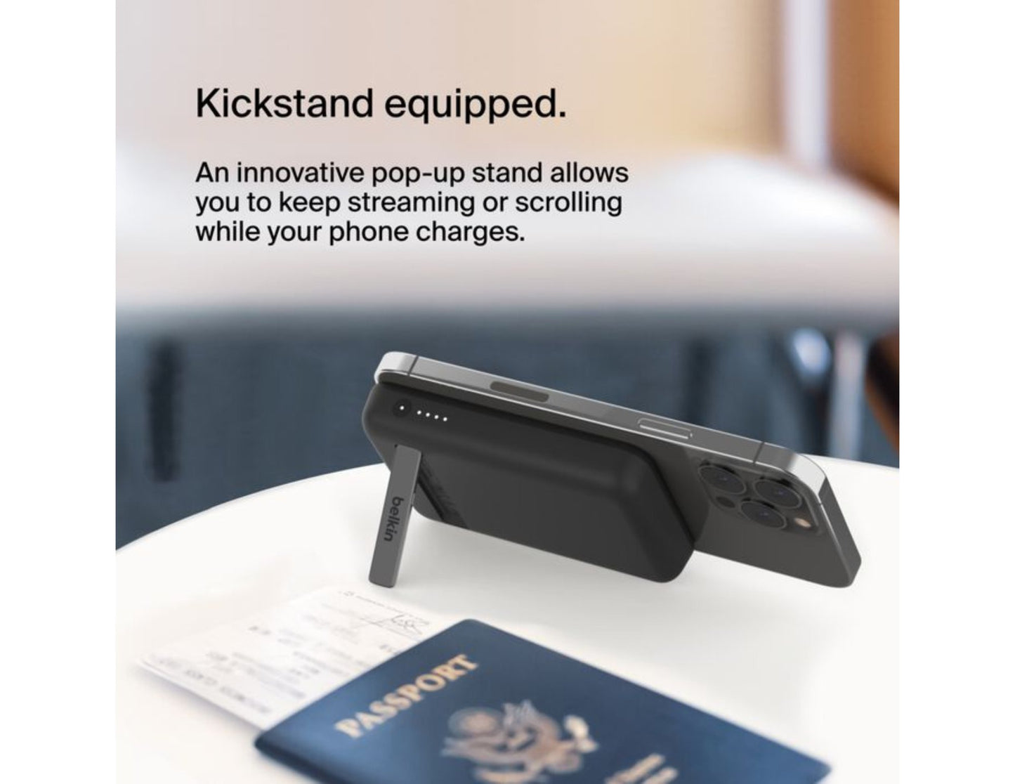 Belkin BoostCharge Magnetic Wireless Power Bank 5000mAh with Fold-out Stand – BPD004btBK – Black on a table next to a passport