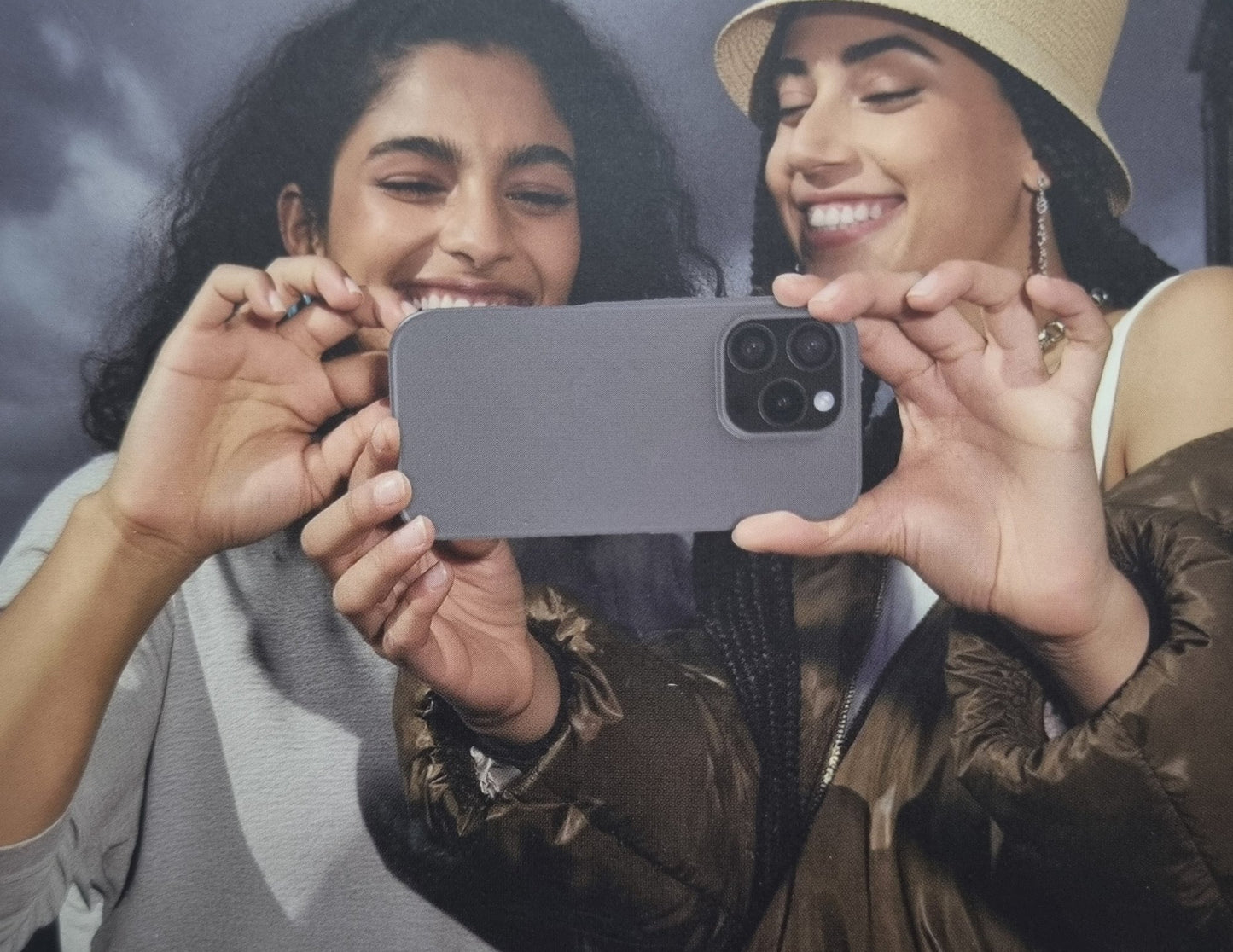 Two women holding a smartphone together, smiling.