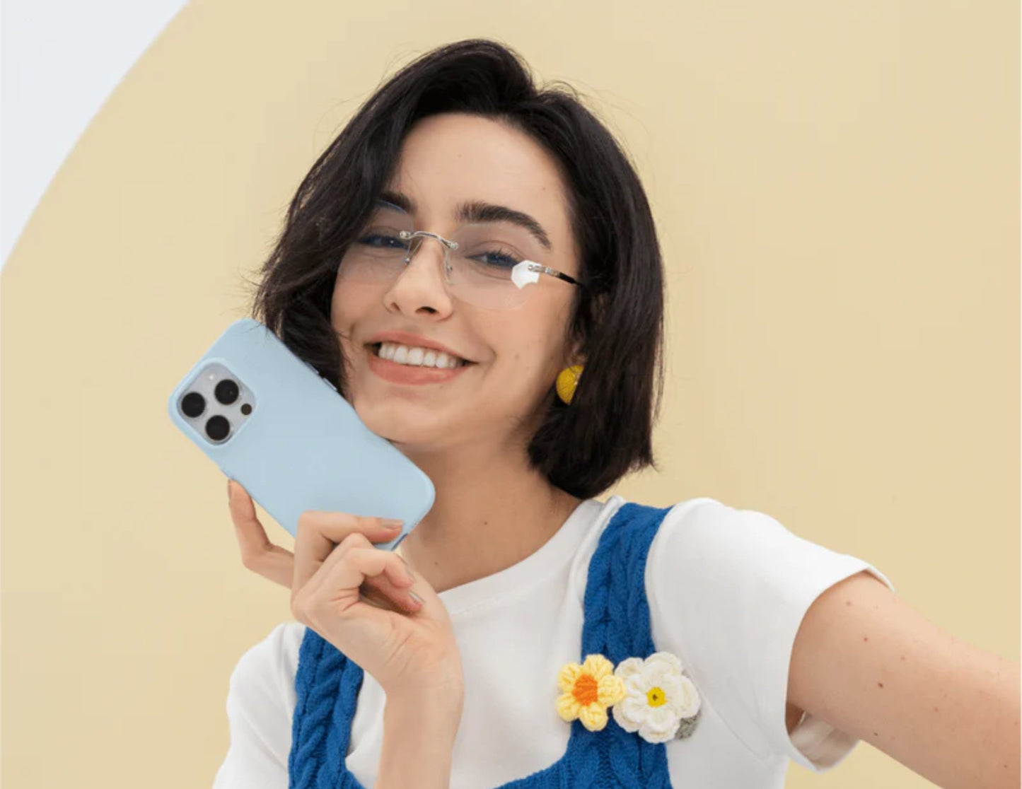 Woman holding a phone with a light blue case against a beige background