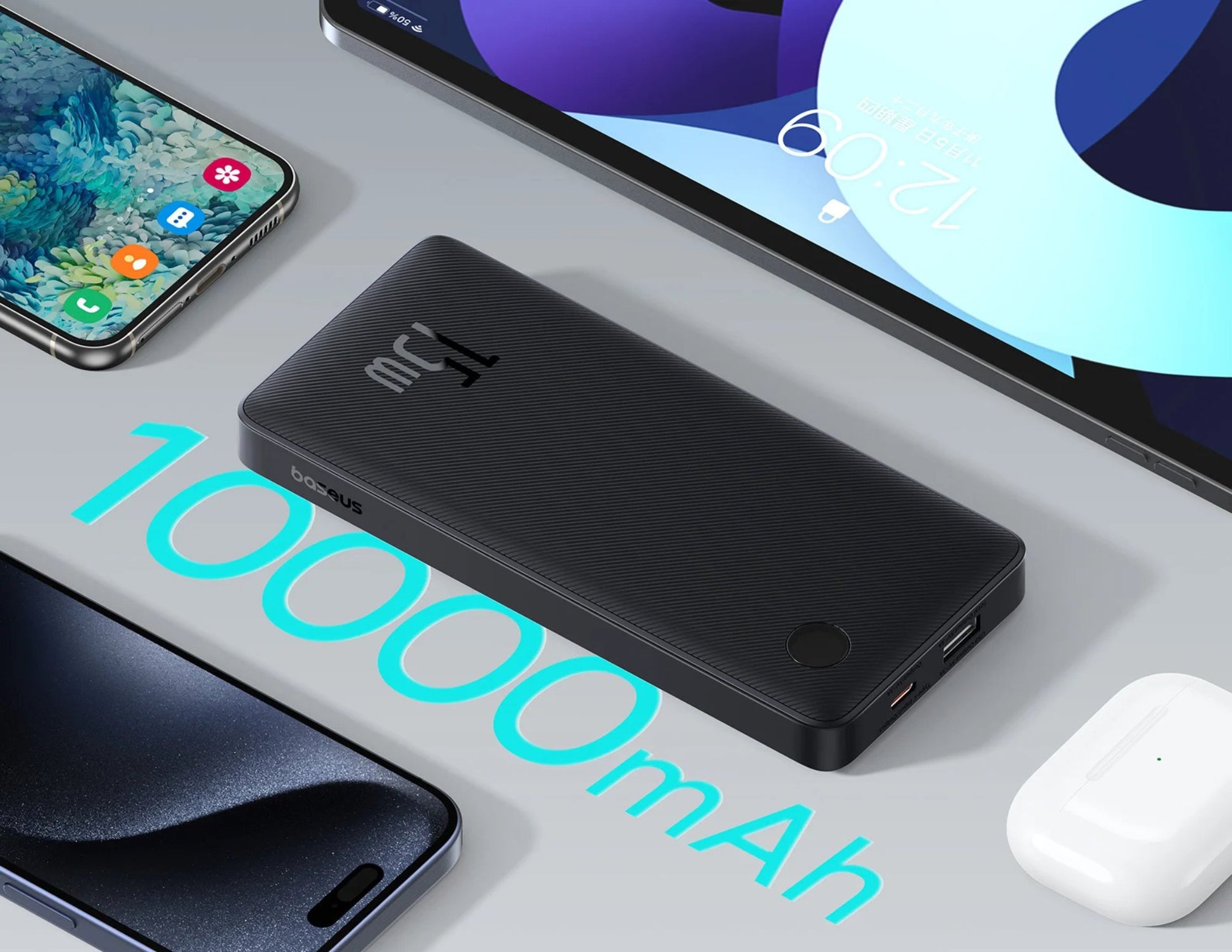 Black power bank with '10000mAh' text on a gray surface with electronic devices.