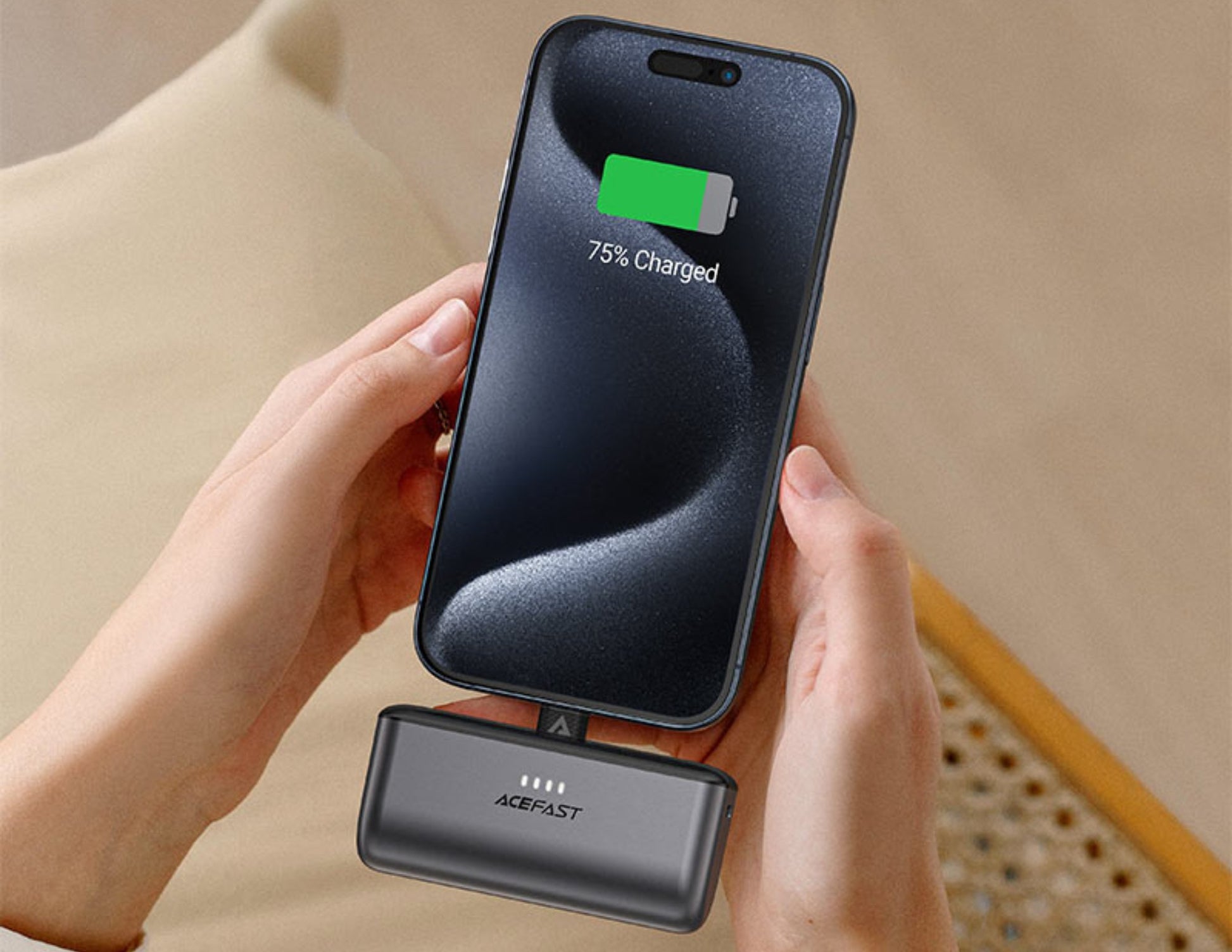 Person holding a smartphone with a charging case on a beige surface