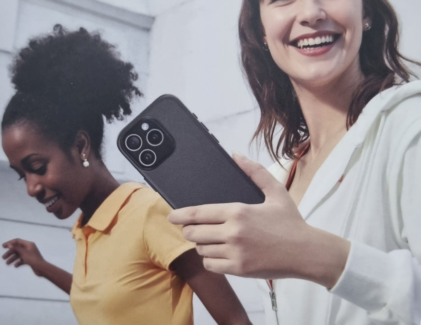 Two women looking at a phone together, one holding it.