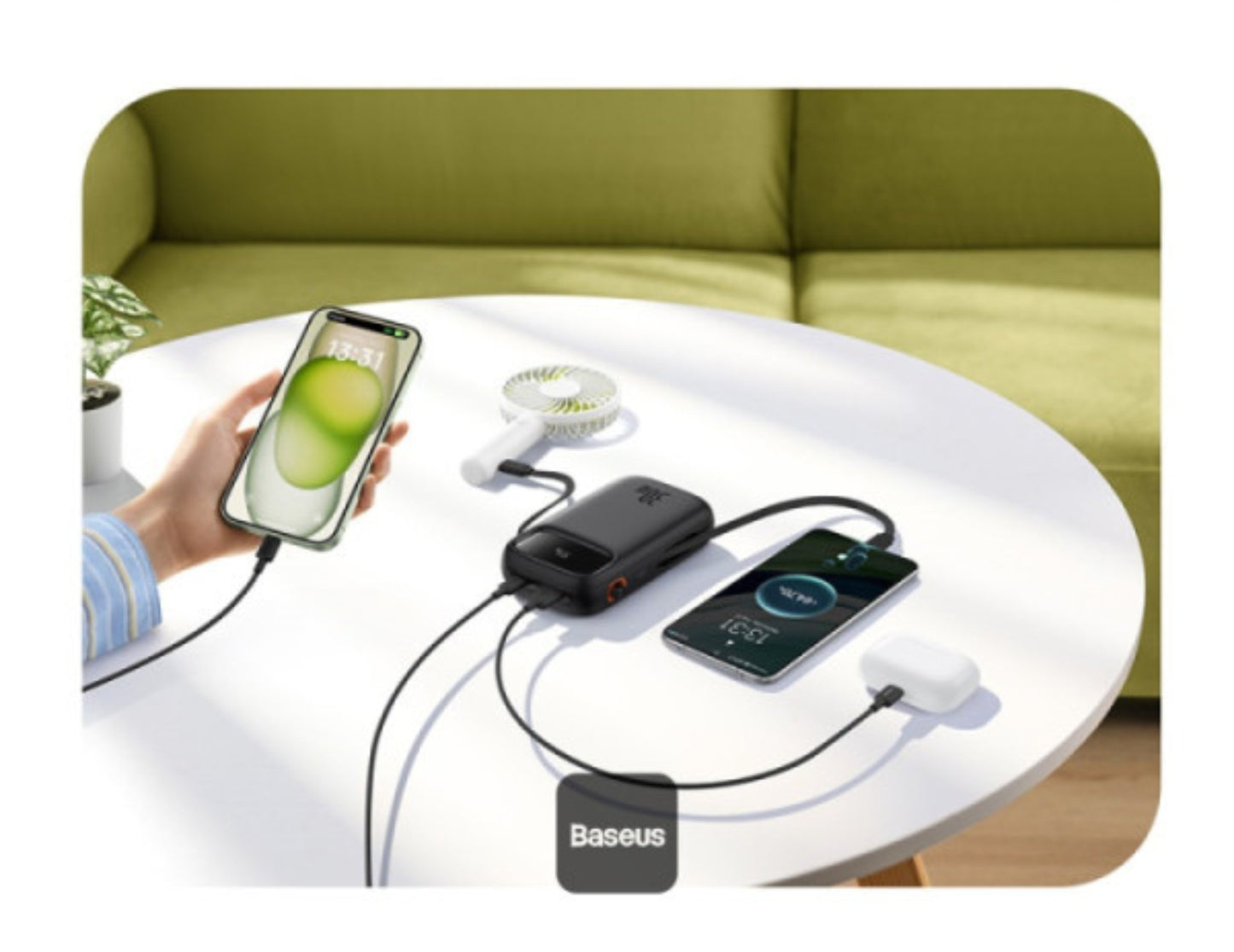 Baseus power bank charging two smartphones on a table with a green sofa in the background