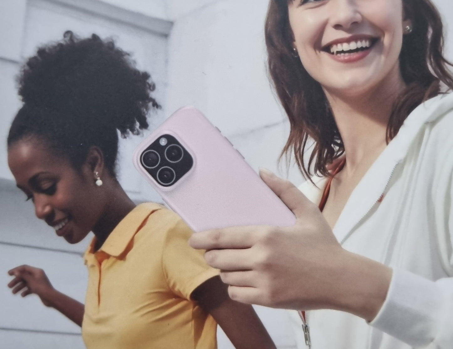 Two women holding a pink smartphone with a white background