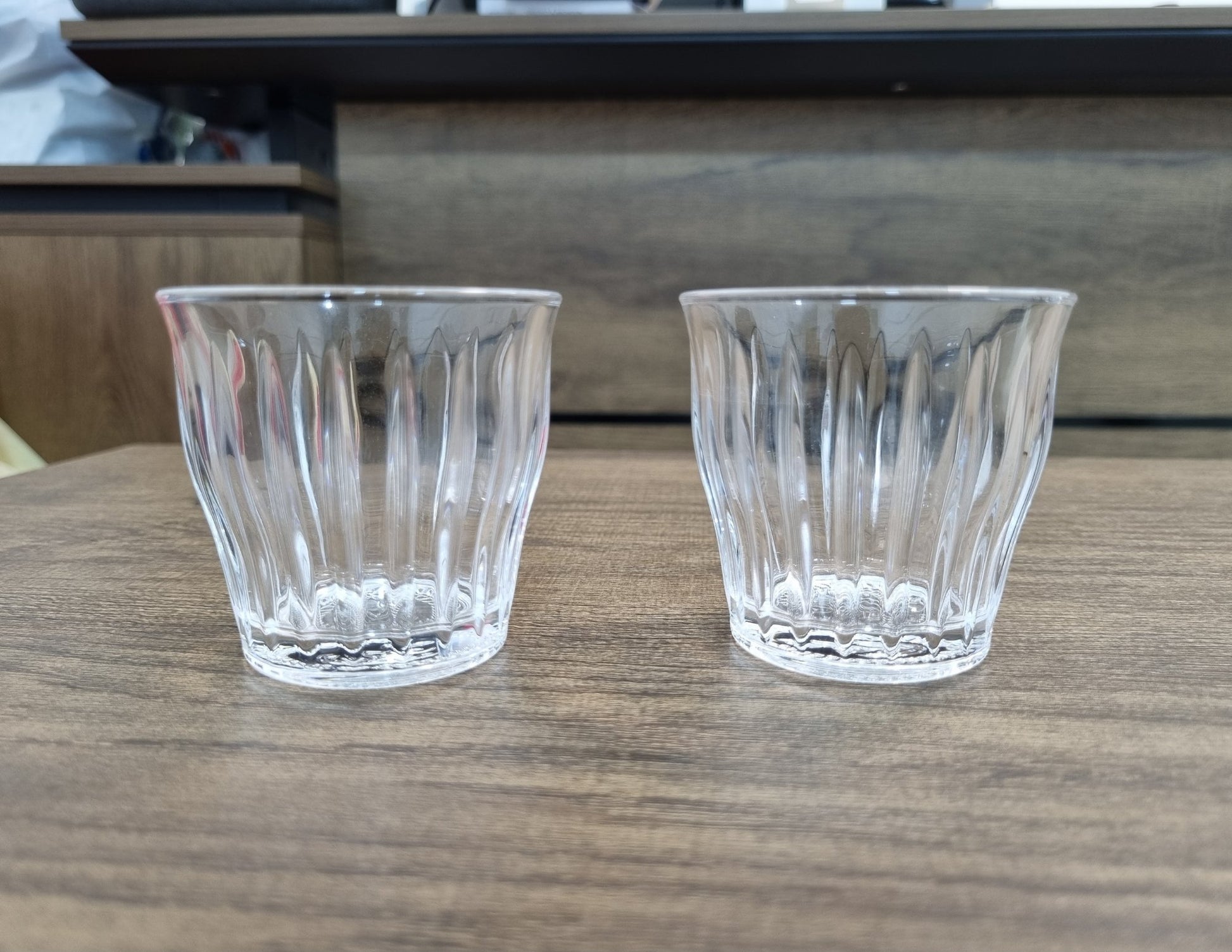 Two clear glass tumblers on a wooden surface