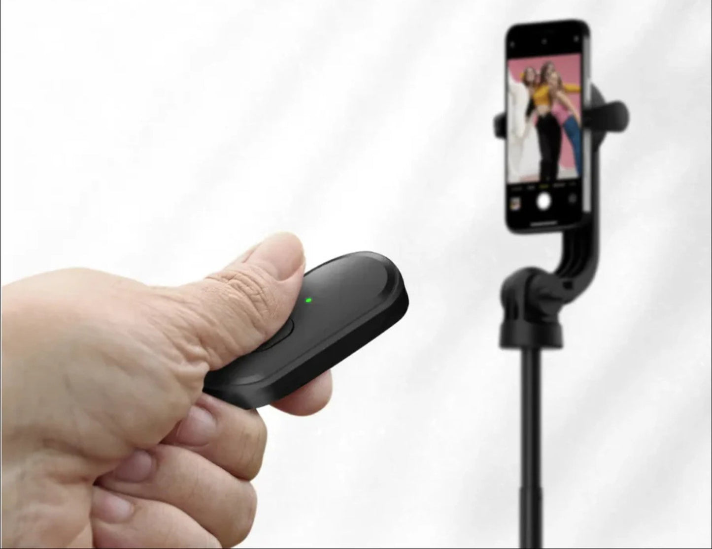 Hand holding a black smartphone gimbal with a phone displaying a photo on a white background