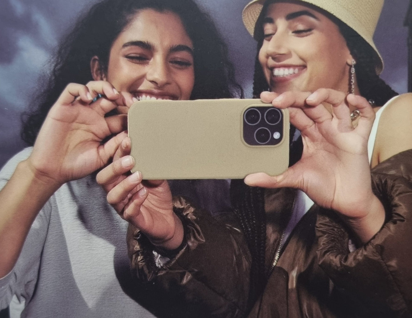 Two women taking a selfie with a phone, with a blurred background