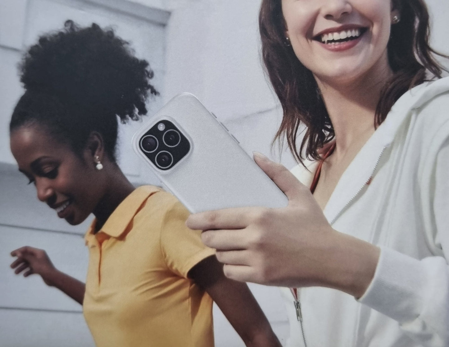 Two women looking at a phone with a white background