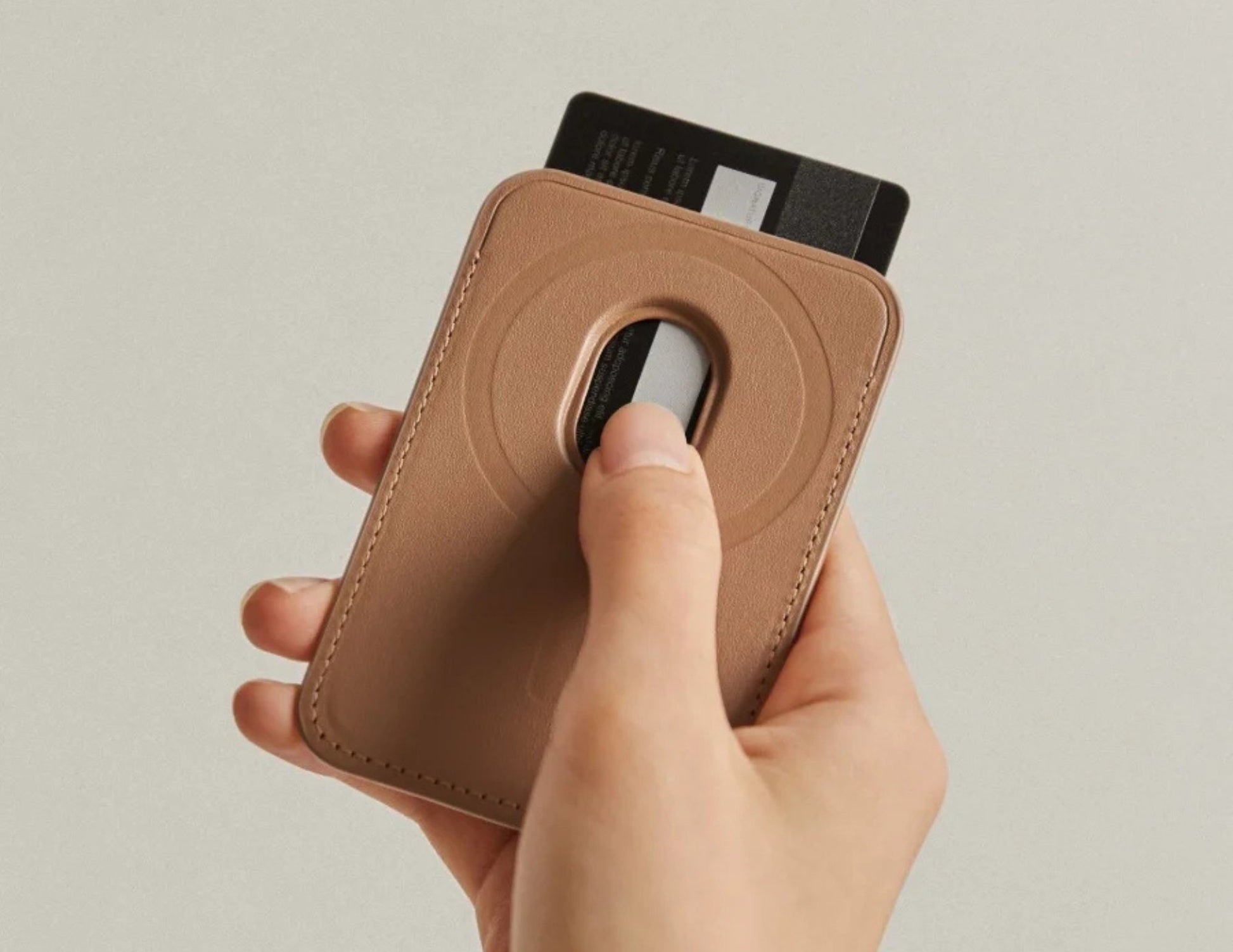 Hand holding a Pitaka MagSafe Woven Wallet – Magsafe Compatible MWW240 with a card inserted on a beige background