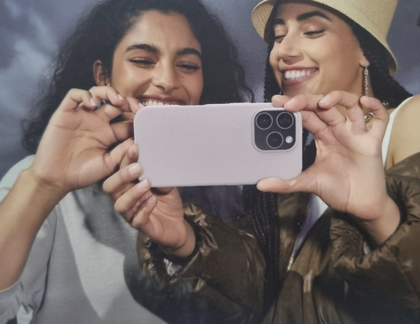 Two women holding a phone together, smiling.