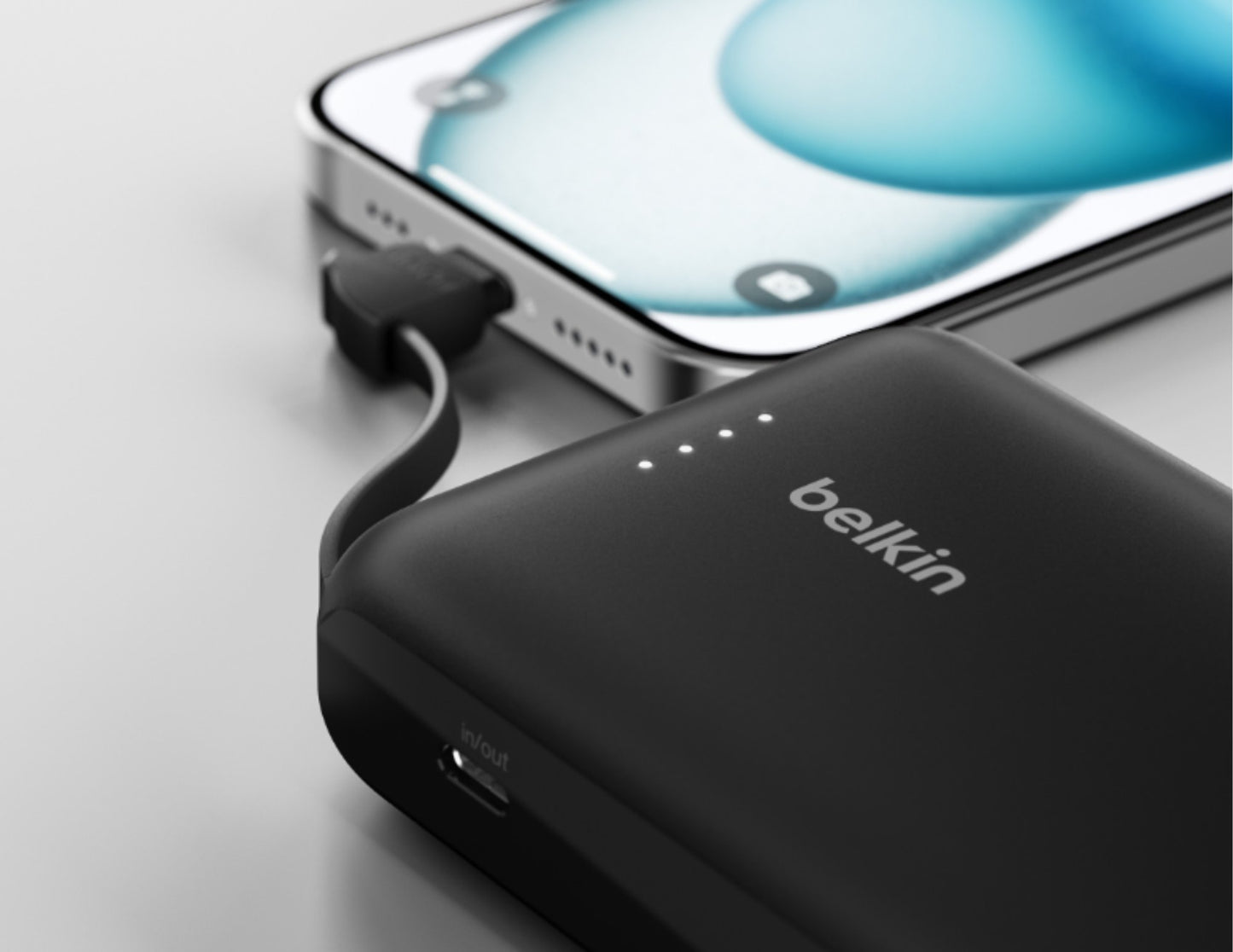 Black Belkin BoostCharge BPB021hq 10K 20W power bank with USB-C cable from Thabthaba Store connected to a smartphone on a light gray background