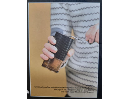 Person using a manual coffee grinder with text overlay on a beige background