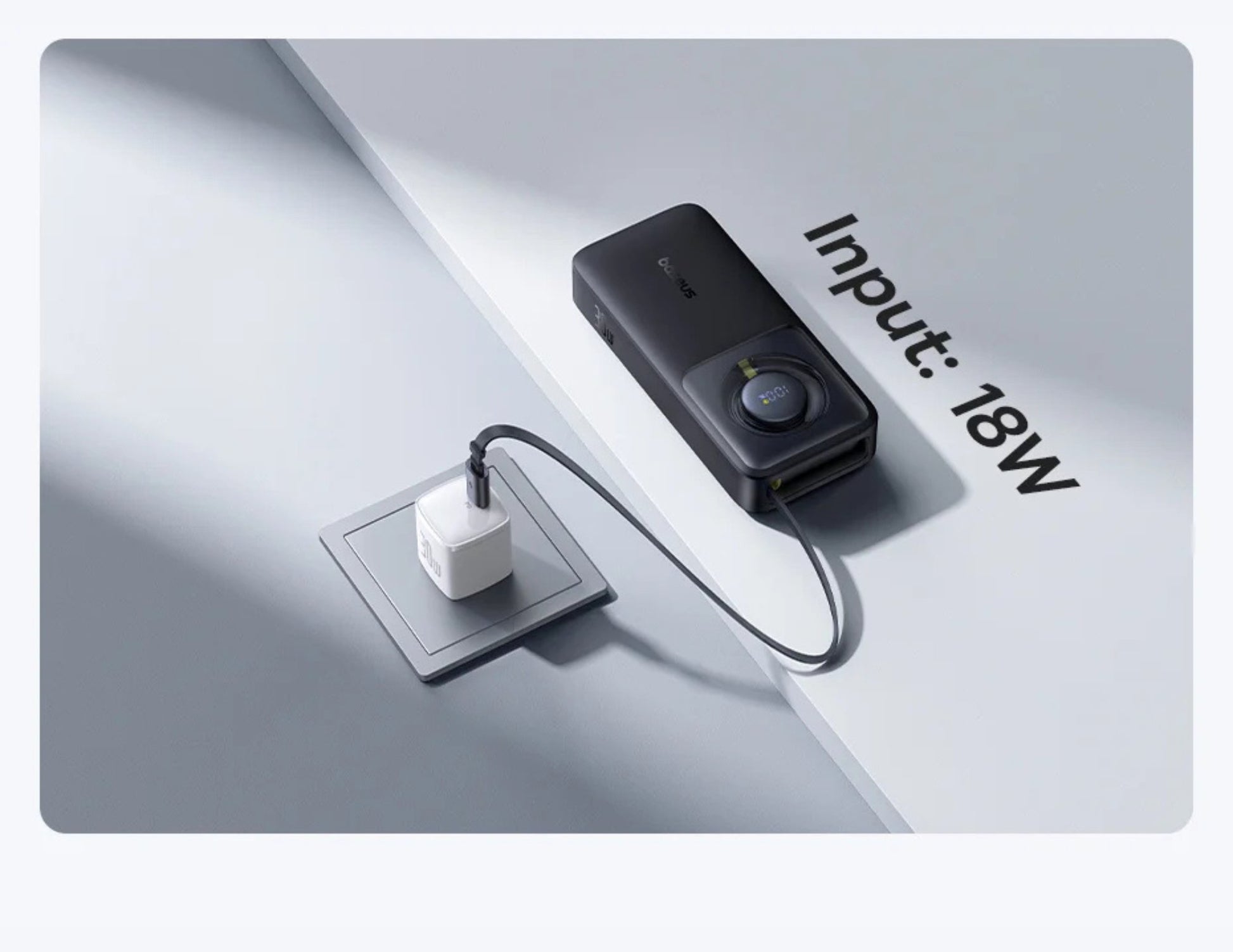 Black electronic device with a cable plugged into a white square socket on a light gray background.