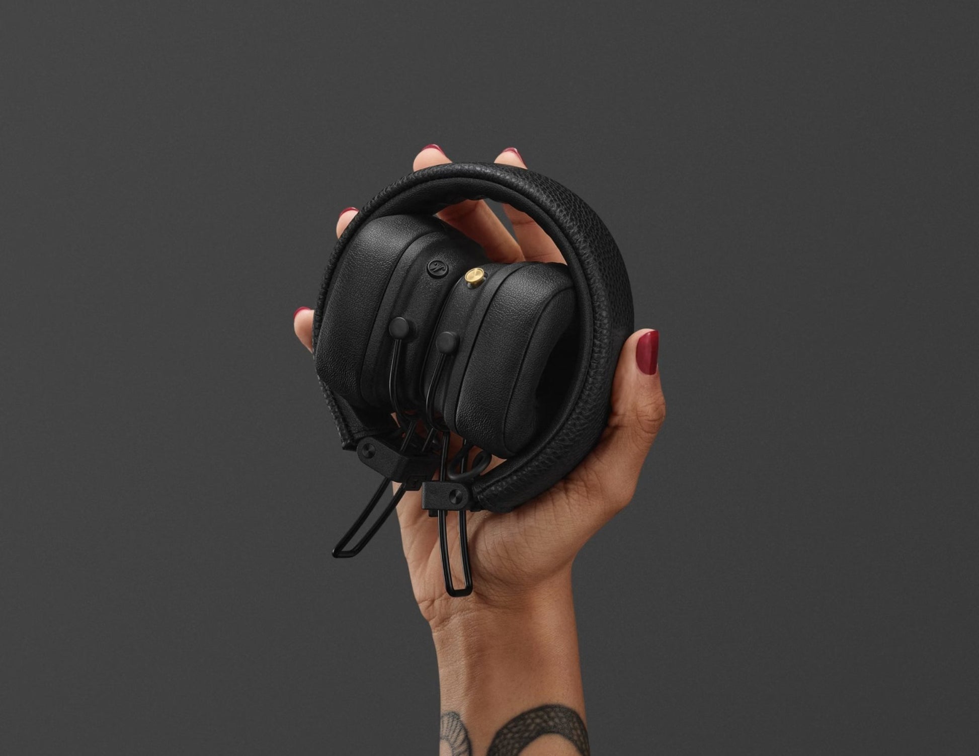 Black headphones held by a hand against a dark background