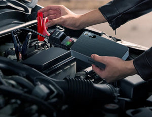 Person using a portable jump starter to charge a car battery