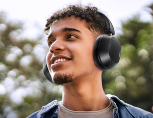 Person wearing black headphones outdoors with a blurred natural background