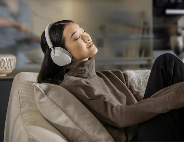 Woman wearing headphones and relaxing on a couch in a home setting