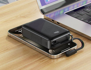 Phone with a Acefast M4 20000mAh Power Bank attached on a wooden surface next to a laptop.