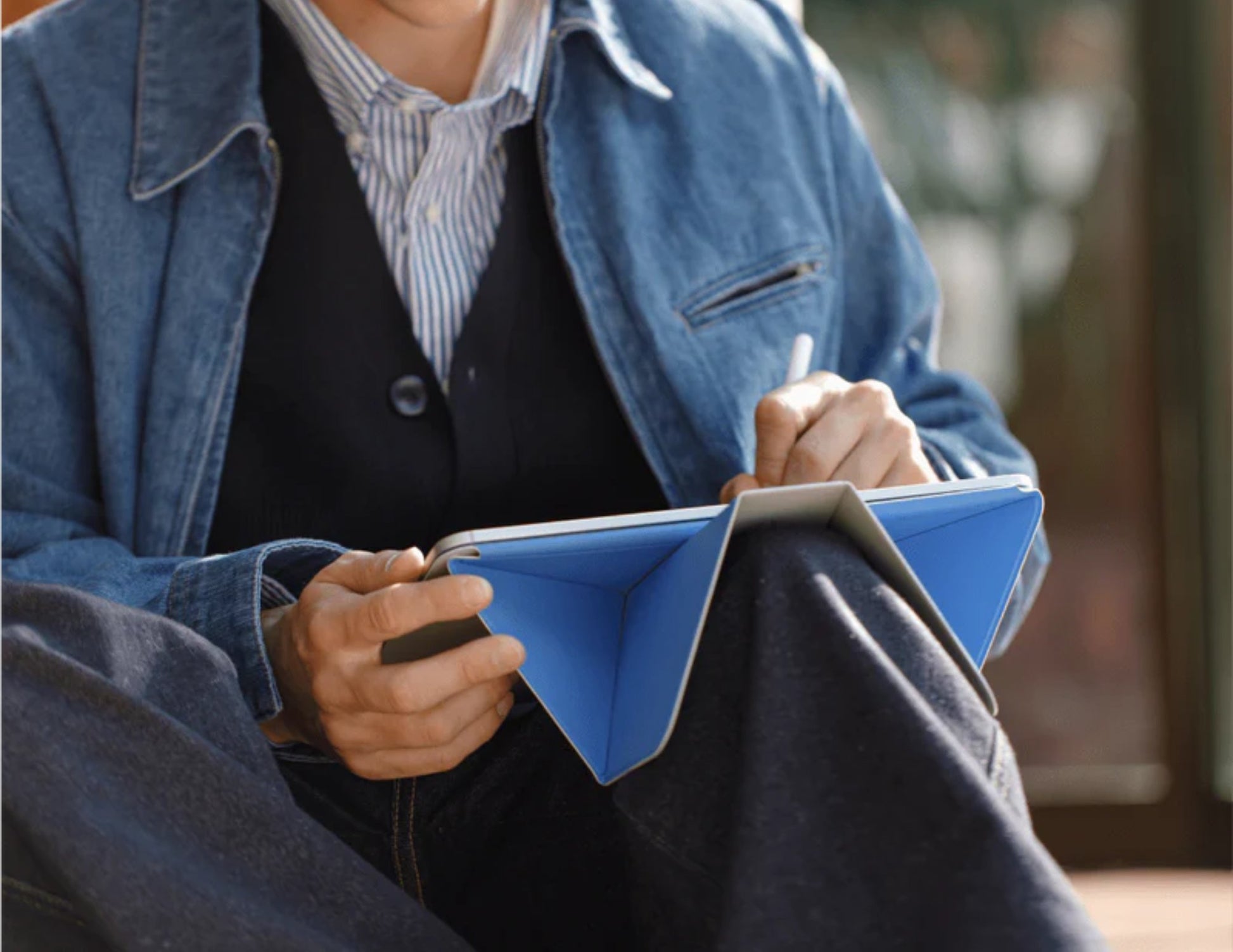 Person in a blue jacket holding a blue notebook with Moft Dynamic Folio Case for iPad Pro 11-inch (M4) and pen.