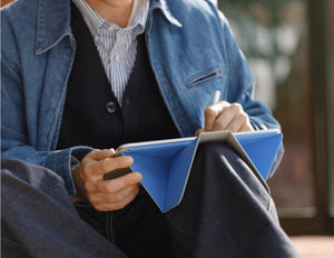 Person in a blue jacket holding a blue notebook with Moft Dynamic Folio Case for iPad Pro 11-inch (M4) and pen.