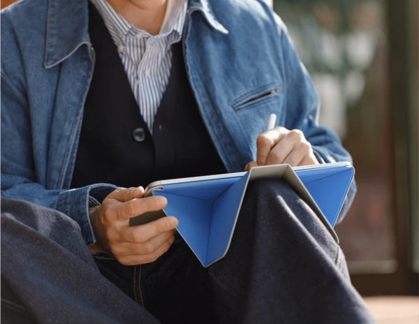 Person in a blue jacket holding a blue notebook with Moft Dynamic Folio Case for iPad Pro 11-inch (M4) and pen.