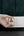 Hand holding a Momax 1‑World² 5‑Port Mini Universal Travel GaN Charger 70W with Dual AC – UA22L2 against a dark background