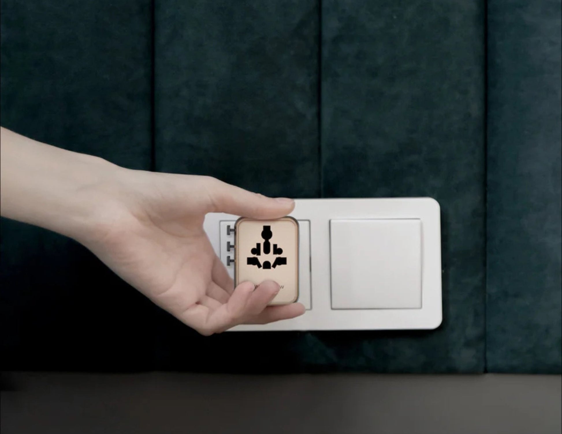 Hand holding a Momax 1‑World² 5‑Port Mini Universal Travel GaN Charger 70W with Dual AC – UA22L2 against a dark background